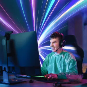 Male gamer sat at a computer desk wearing a headset and gaming on a pc