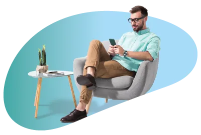A man wearing glasses sat on a chair looking at his phone with a side table beside him