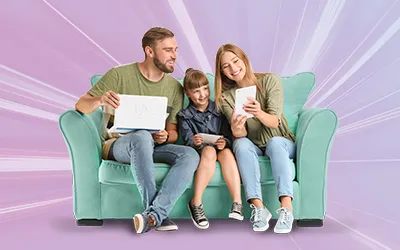 Young family sat on a sofa all using electronic devices