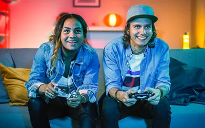 Young adult gamers one male and female holding games controllers immersed in gaming